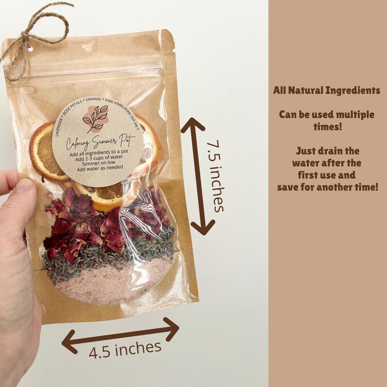 Op de afbeelding: Een bruine kraftpapieren zak met gedroogde sinaasappelschijfjes, rozenblaadjes, lavendel en roze Himalayazout. Het etiket vermeldt Calming Simmer Pot. De zak is 19,05 cm hoog en 11,43 cm breed, met tekst over de natuurlijke ingredi&euml;nten.