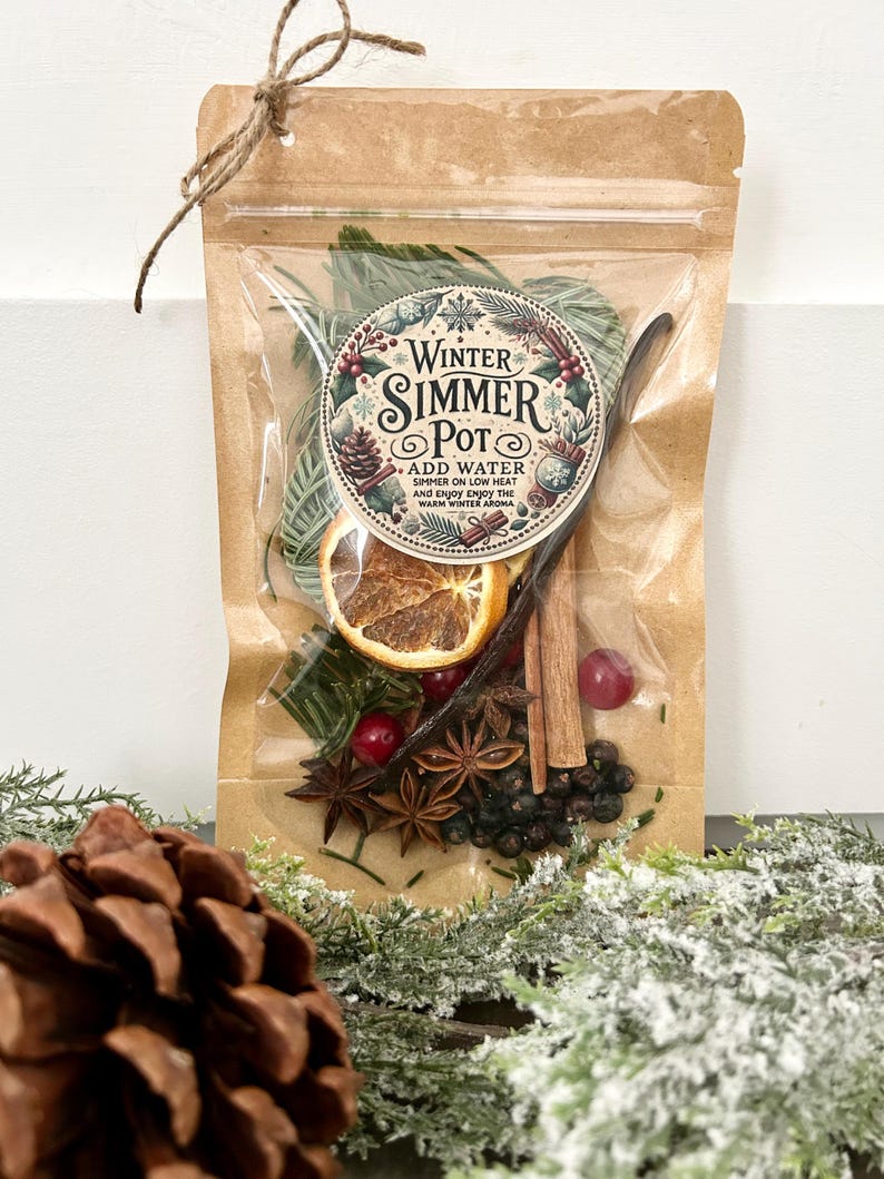 Pu&ograve; includere: Un sacchetto di carta marrone con una finestra di plastica trasparente che contiene un mix di ingredienti secchi per un simmer pot invernale. Il sacchetto ha un'etichetta rotonda con il testo "Winter Simmer Pot" e istruzioni per aggiungere acqua e far sobbollire a fuoco lento per godere del caldo aroma invernale.
