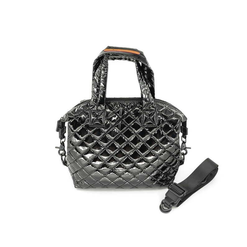 May include: A black quilted handbag with a top handle and a detachable shoulder strap. The bag has a shiny, almost metallic finish.