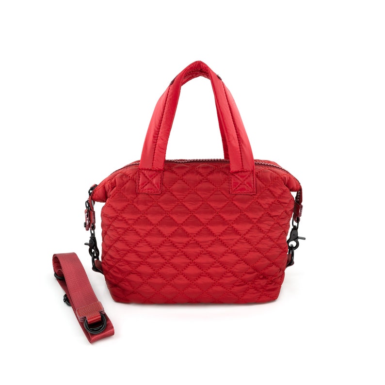 May include: A red quilted handbag with a top handle and a detachable shoulder strap. The bag has a diamond-shaped quilted pattern.