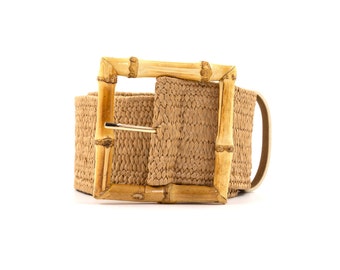May include: A woven brown belt with a natural bamboo buckle. The belt is made of a woven material and has a rectangular buckle.