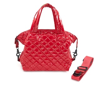 K&ouml;nnte beinhalten: Eine gl&auml;nzende rote Handtasche mit einem Steppmuster. Die Tasche hat zwei obere Griffe und einen abnehmbaren Schultergurt. Die Hardware ist schwarz. Die Tasche befindet sich auf wei&szlig;em Hintergrund.