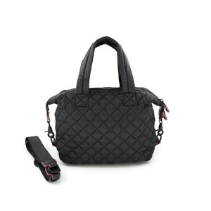 K&ouml;nnte beinhalten: Schwarze, gesteppte Nylon-Tragetasche mit Rei&szlig;verschluss oben, zwei Tragegriffen und einem abnehmbaren Schultergurt. Die Tasche hat ein Rautenmuster und rosa Akzente.