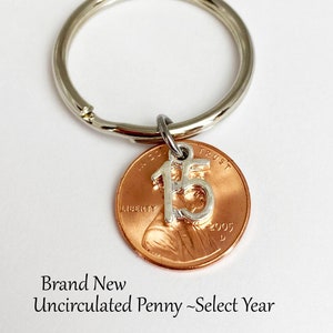 May include: A silver charm with the number 15 attached to a copper penny keychain. The penny is dated 2005. Brand New Uncirculated Penny - Select Year.