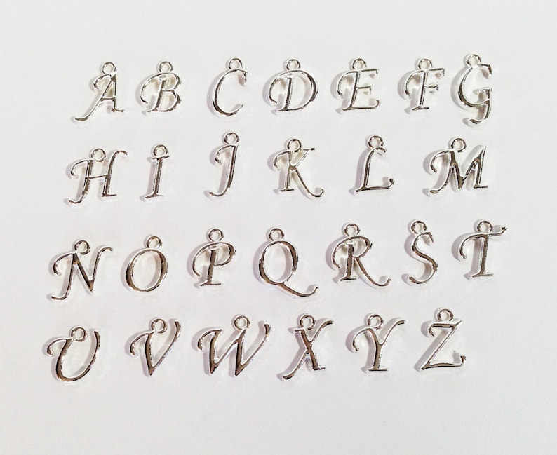 May include: A set of 26 silver-colored metal alphabet letter charms. Each letter is in a cursive font style.