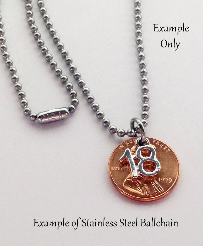 K&ouml;nnte beinhalten: Eine silberne Kugelkette mit einem 1999 US-Penny-Anh&auml;nger mit der Zahl 18. Der Penny ist kupferfarben und die Zahl 18 ist silber.
