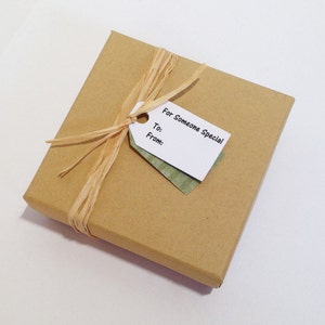 May include: A brown gift box with a white gift tag that says "For Someone Special" and has spaces for "To:" and "From:". The box is tied with a natural raffia ribbon.