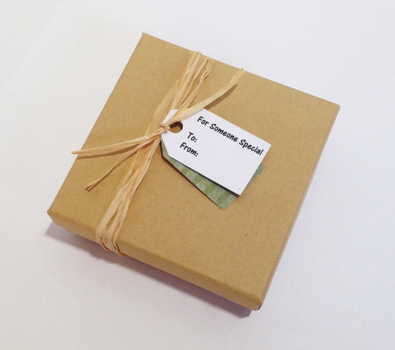 May include: A brown gift box with a white gift tag that says "For Someone Special" and has spaces for "To:" and "From:". The box is tied with a natural raffia ribbon.