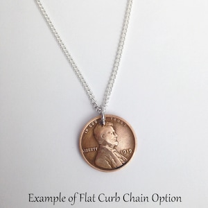 May include: A silver chain necklace with a 1919 penny pendant. The penny features a profile of Abraham Lincoln with the words "In God We Trust" and "Liberty" on the coin.