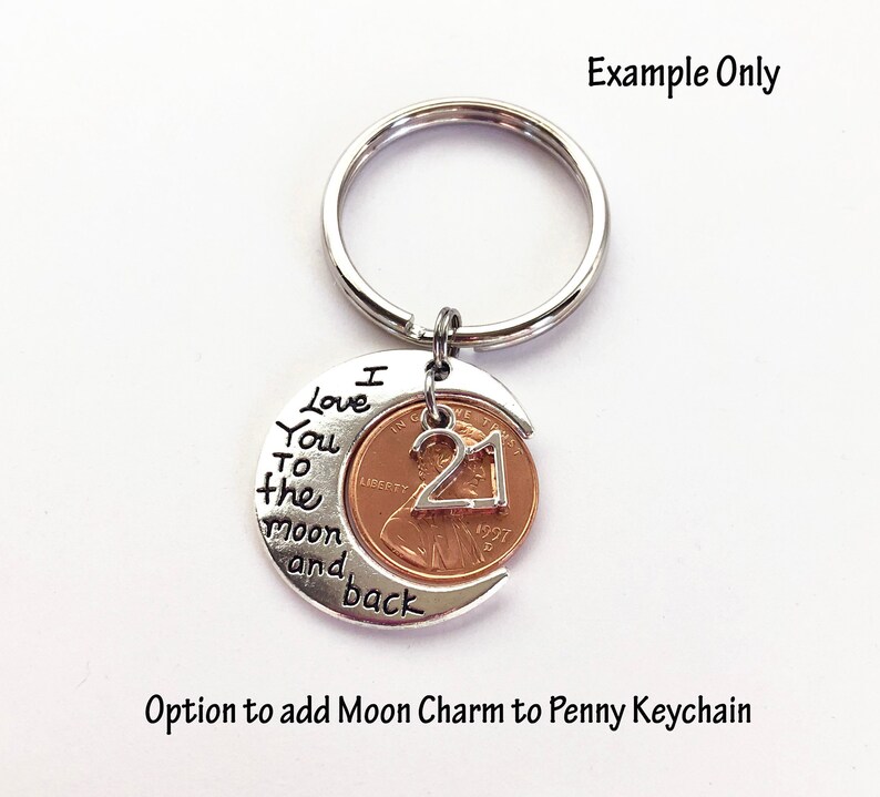 May include: A silver-colored keychain with a penny featuring the number 21. The penny is set in a crescent moon charm with the words "I love you to the moon and back." The keychain is a personalized gift.