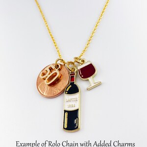 May include: Gold rolo chain necklace with a charm of a wine bottle, a wine glass, and a penny with the number 50 on it.