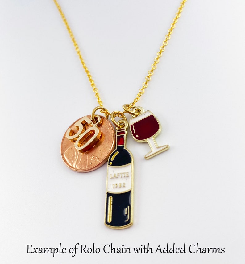 May include: Gold rolo chain necklace with a charm of a wine bottle, a wine glass, and a penny with the number 50 on it.