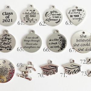 May include: Assortment of silver charm pendants with inspirational quotes and graduation themes.  The charms feature phrases like "She believed she could so she did", "You were made to make a difference", and "Let your dreams be your wings".  There are also graduation caps with the year 2021 and 2022.