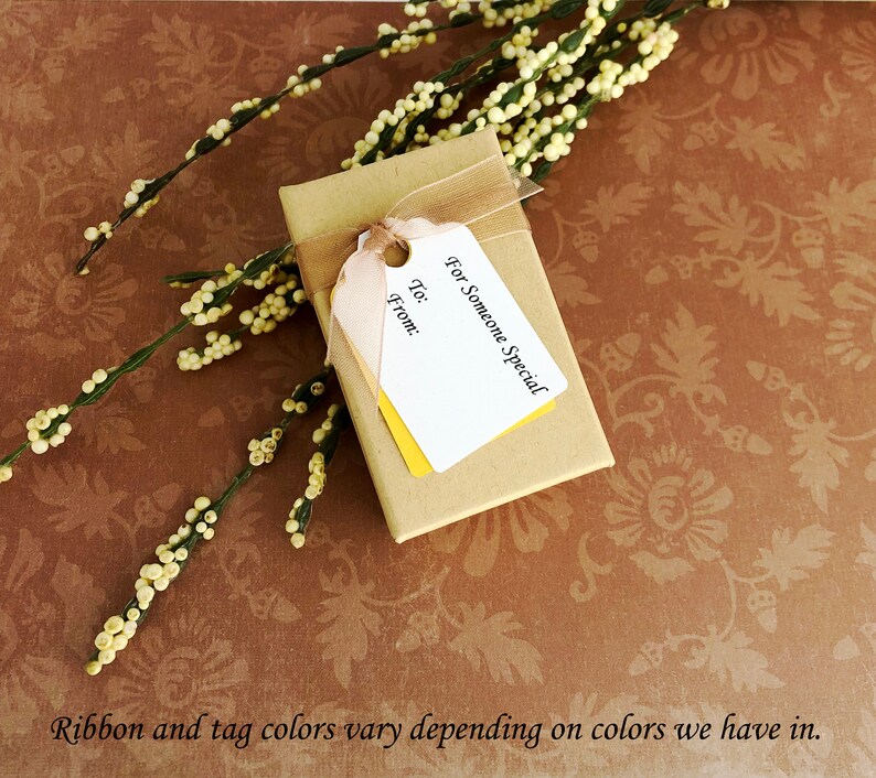 May include: A small brown gift box with a white tag that says "For Someone Special" and has spaces to write "To:" and "From:". The box is tied with a brown ribbon and is sitting on a brown background with a floral pattern.