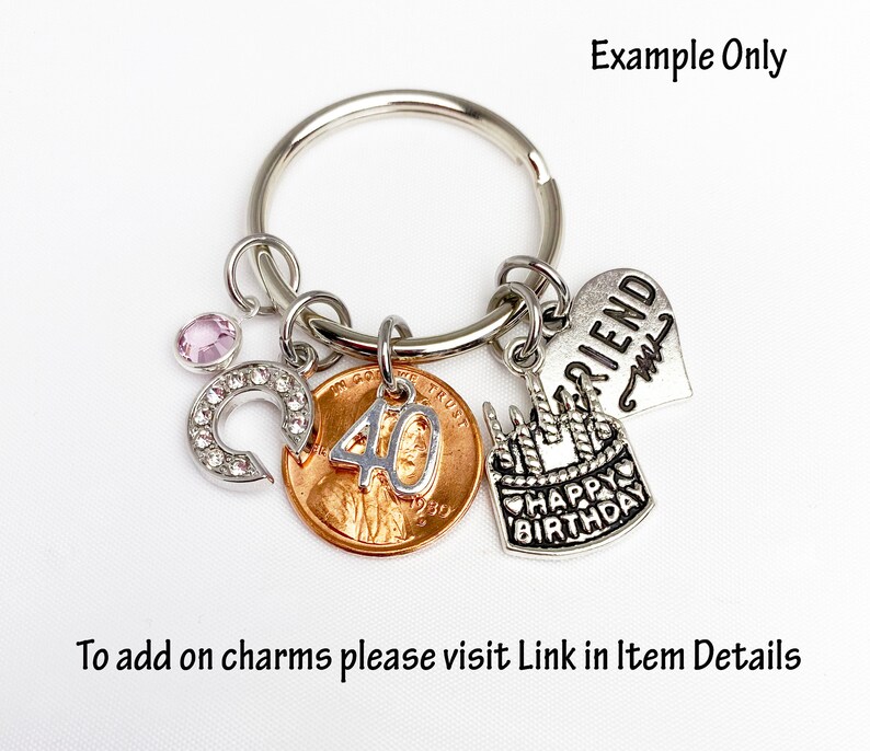 May include: A silver keychain with multiple charms. Charms include a penny with the number 40, a horseshoe with rhinestones, a heart with the word "FRIEND", and a birthday cake. The text "HAPPY BIRTHDAY" is on the cake charm.
