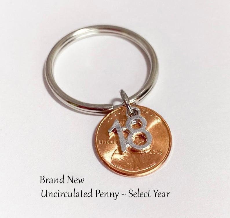 18th Birthday Penny Keychain, Comes with penny representing the birth year and 18 number charm on keyring. Number charm dangles on top of penny.