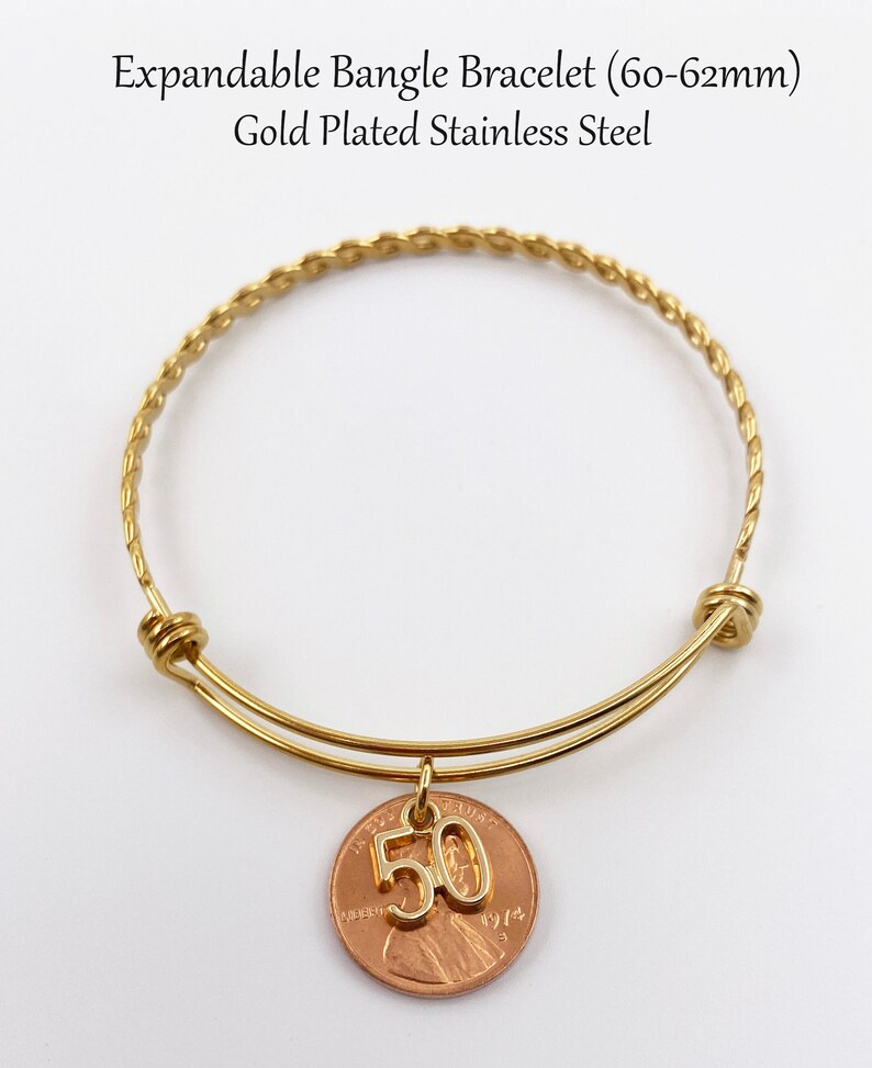 May include: Gold-plated expandable bangle bracelet with a charm featuring a penny with the number 50 on it. The bracelet is 60-62mm in size.