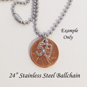 May include: A silver-colored number 50 charm pendant hangs from a stainless steel ball chain necklace. The pendant is attached to a copper penny. The text "Example Only" is visible. The necklace is 24 inches long.