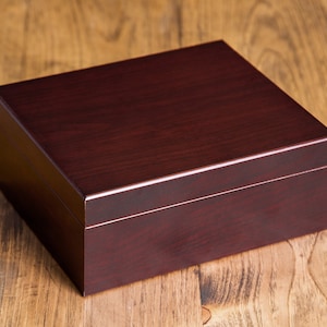 May include: A dark brown wooden box with a smooth, polished finish. The box has a hinged lid and is ideal for storing small items.