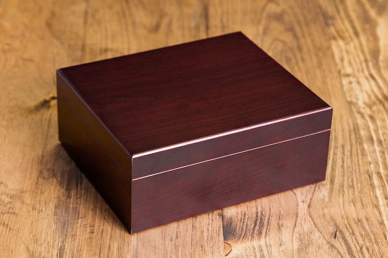 May include: A dark brown wooden box with a smooth, polished finish. The box has a hinged lid and is ideal for storing small items.