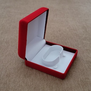 May include: A red velvet jewelry box with a white interior and a ring holder.