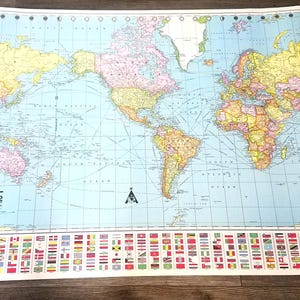 May include: A colorful world map with country borders in various colors, including yellow, pink, and green, against a light blue background. The map includes a key of flags at the bottom. The title "THE WORLD" is printed in black.
