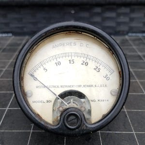 May include: Vintage black and white analog ammeter with the text "AMPERES D.C." and a scale from 5 to 30. The gauge is marked "WESTON ELECTRICAL INSTRUMENT CORP., NEWARK, N.J., U.S.A." and "MODEL 301".