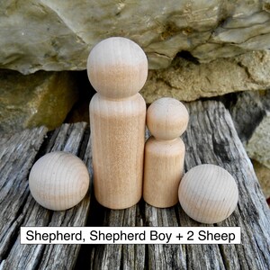 May include: A wooden toy set featuring a shepherd, a shepherd boy, and two sheep. The figures are made of natural wood and have a simple, rounded design. The text "Shepherd, Shepherd Boy + 2 Sheep" is displayed at the bottom.