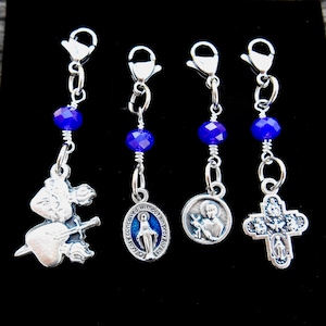 Può includere: Quattro ciondoli in argento con perline di cristallo blu e chiusure in argento. I ciondoli includono un Sacro Cuore, una medaglia miracolosa, una medaglia di Sant'Antonio e un crocifisso.