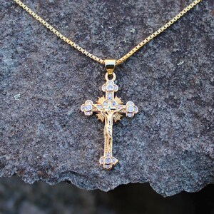 May include: A gold chain necklace with a gold and clear crystal Jesus on the cross pendant.