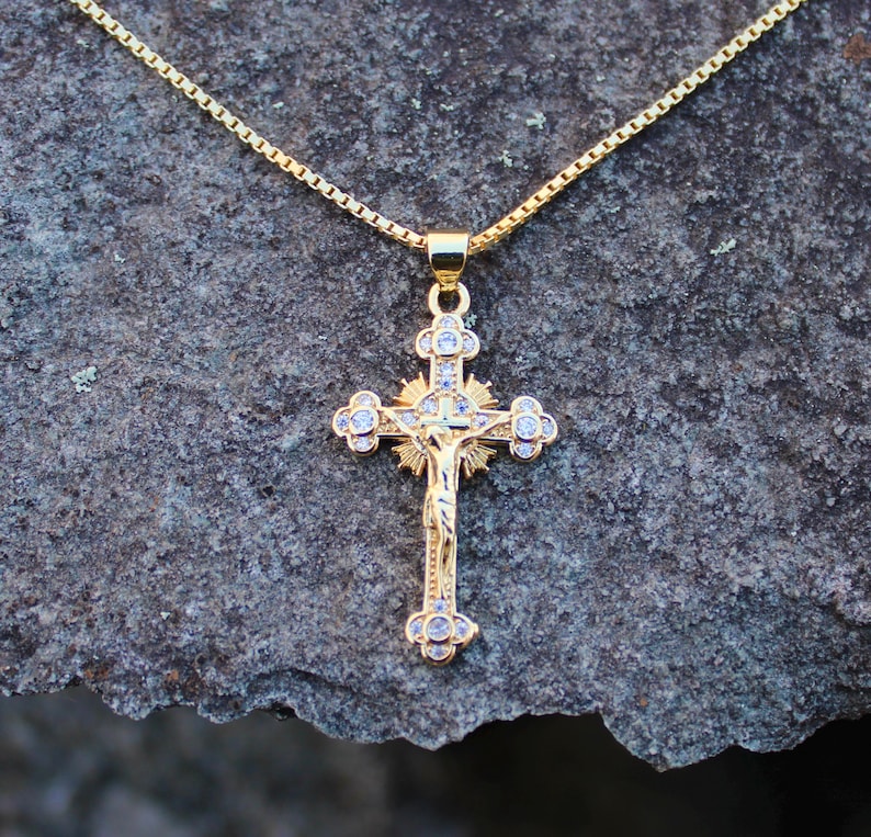 May include: A gold chain necklace with a gold and clear crystal Jesus on the cross pendant.