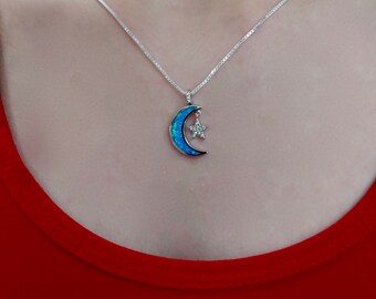 Puede incluir: Un collar de cadena de plata con un colgante de media luna con una piedra de ópalo azul y una estrella con piedras de circonita cúbica transparentes.