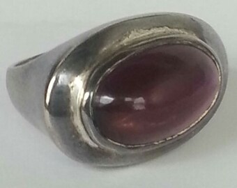 May include: A silver ring with a large, oval-shaped, purple gemstone.