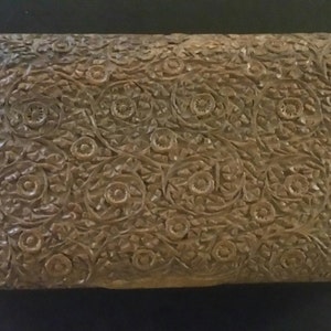 May include: A wooden box with a carved floral design. The box is brown and has a rectangular shape.