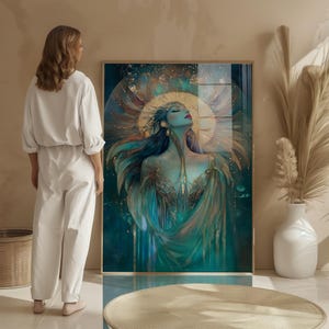 May include: A framed art print depicting a celestial woman with flowing teal and gold robes, a golden halo, and closed eyes. The artwork has a dreamy, ethereal quality, with a dark teal background and gold accents. The woman is the focal point.