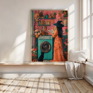Peut inclure: Une femme portant un chapeau de sorci&egrave;re et une robe fleurie se tient dans une pi&egrave;ce avec une machine &agrave; laver et des plantes. Elle lit un livre. Un chat noir est assis sur le sol devant la machine &agrave; laver.