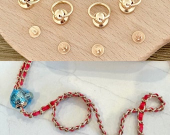 May include: Gold-colored metal hardware for bag making, including ring clasps and rivets. A red and gold chain with the word "love" spelled out in the chain's design is also shown. A blue, faceted bead is attached to the chain.