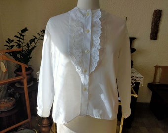 May include: A white long-sleeved blouse with a lace collar and button fastening.