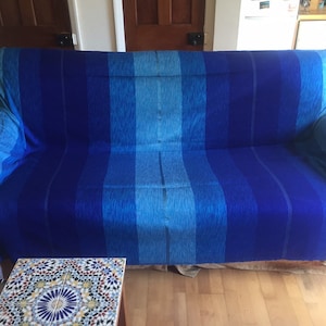 May include: A blue and turquoise striped throw blanket draped over a sofa.