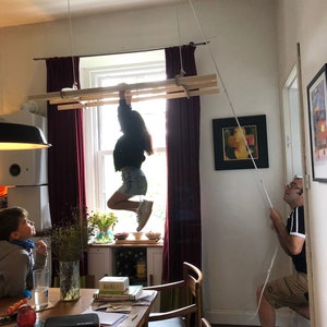 child is pulled up to the ceiling whilst hanging on to a ceiling mounted clothes dryer made by branches of hogan