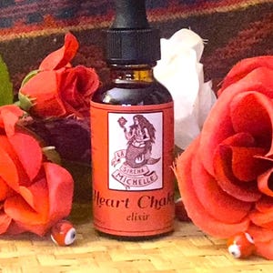 May include: A brown glass bottle with a black dropper, labeled "Heart Chakra elixir" with a mermaid illustration. The bottle is surrounded by vibrant red roses and decorative elements, creating a natural and artistic display.