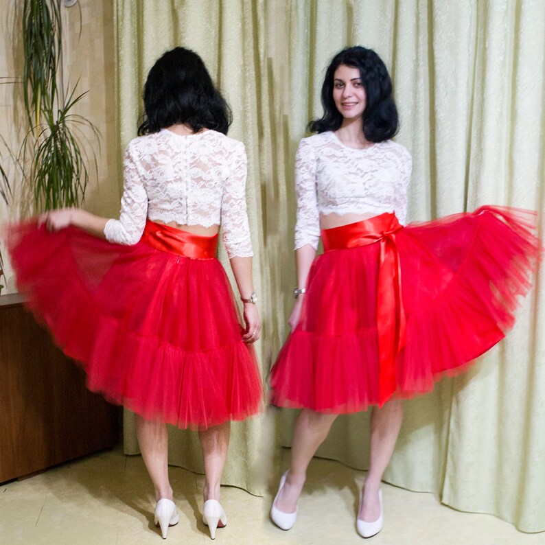 May include: A red tulle skirt with a white lace top and a red satin ribbon tied around the waist.