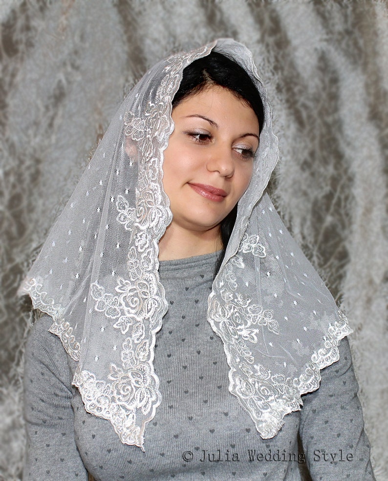 May include: A white lace veil with a delicate floral pattern. The veil is sheer and has a scalloped edge.