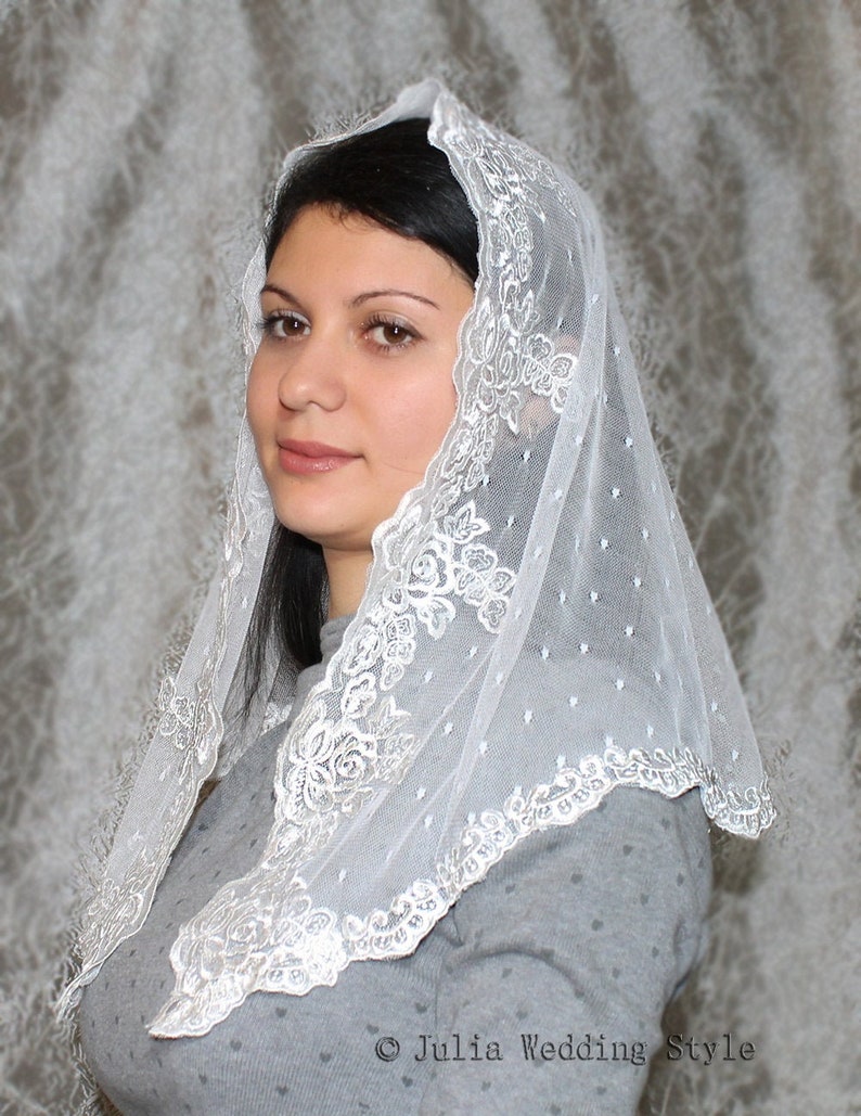 May include: White lace veil with a scalloped edge and floral pattern. The veil is worn by a person with dark hair.