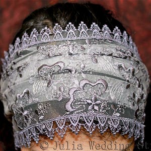May include: A delicate, gray lace veil with a scalloped edge. The veil is made of a sheer fabric with intricate floral embroidery.