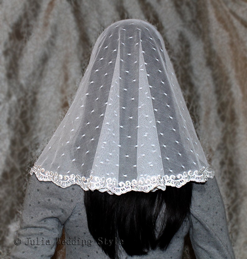 May include: White bridal veil with a dotted pattern and a silver lace trim. The veil is folded in a way that creates a dome shape.