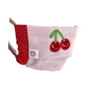 May include: Pink face mask with a red polka dot trim and a cherry embroidery. The mask has a white label with a smiley face.