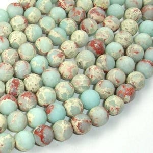 May include: A strand of round, light blue, beige, and red jasper beads. The beads have a mottled, marbled appearance.