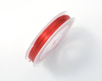 May include: A spool of red elastic string wound around a clear plastic bobbin.