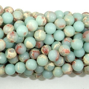 May include: A strand of round, light blue and white jasper beads with red and brown marbling. The beads are approximately 8mm in diameter.